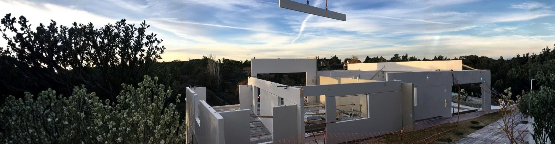 Proceso de construcción industrializada de una casa eficiente con paneles de hormigón y montaje de precisión.